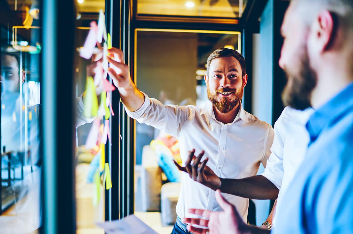 Man reading on tablet outside in front of neon sign